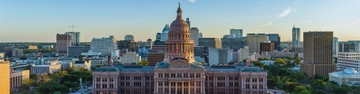 City skyline centred on a domed government building beneath a clear blue sky.