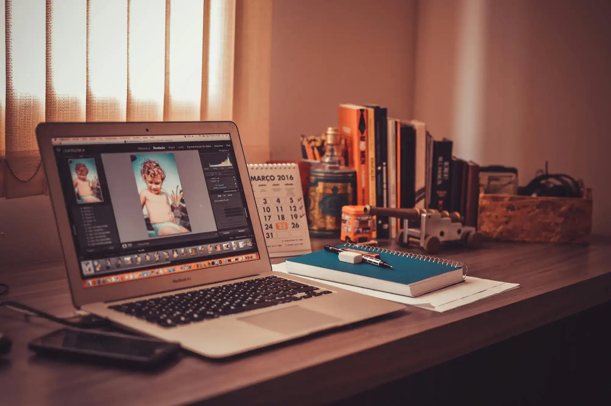 Laptop showing photo editing software on a tidy home office desk.