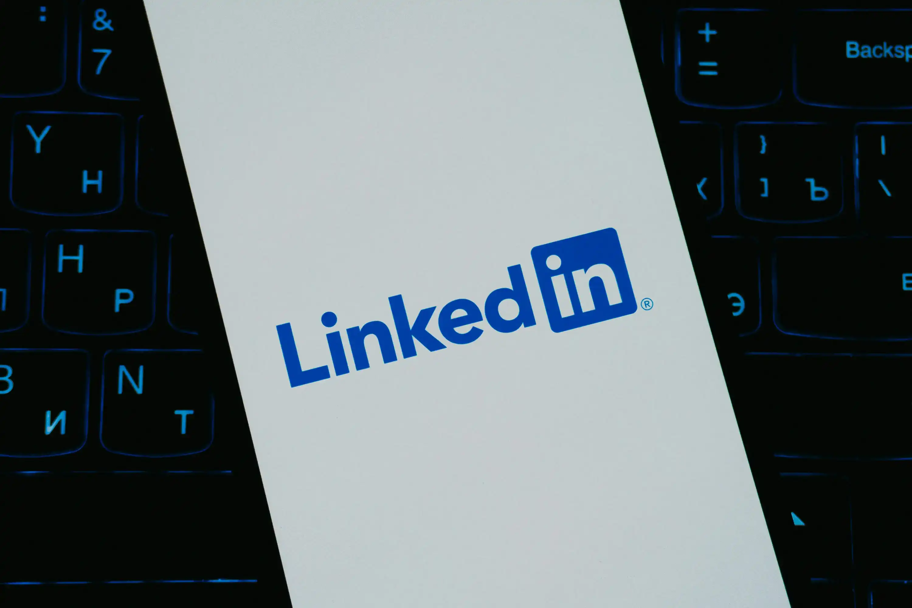 LinkedIn logo displayed on a phone beside a backlit keyboard.